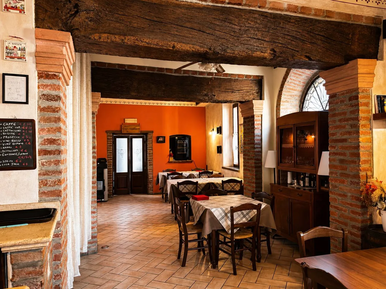 Sala interna dell'Osteria Il Ganascino a San Martino del Lago (Cremona) con travi in legno, archi in mattoni e tavoli apparecchiati.